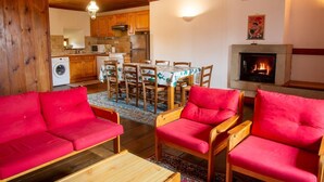 Uma sala de estar aconchegante com sofás vermelhos e um espaço de jantar com mesa e cadeiras.