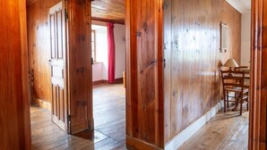 Um interior em madeira com um corredor que leva a um quarto com uma mesa e cadeiras.