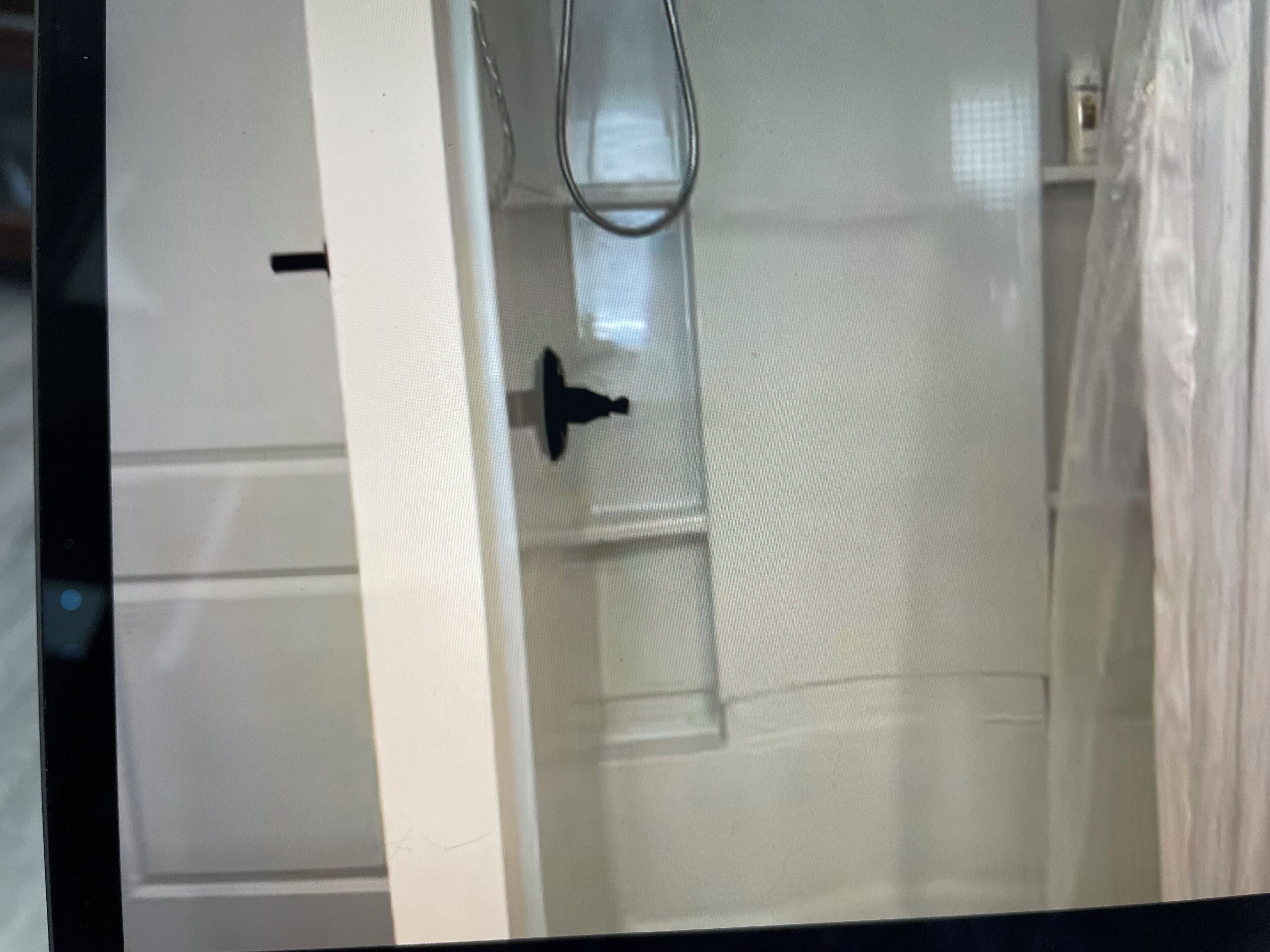 Una puerta blanca con una mirilla, una ventana pequeña y un perchero para toallas.