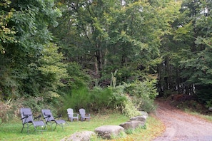 Ein bewaldetes Gebiet mit einem Feldweg, Außenbestuhlung mit Stühlen und einer naturnahen Umgebung.