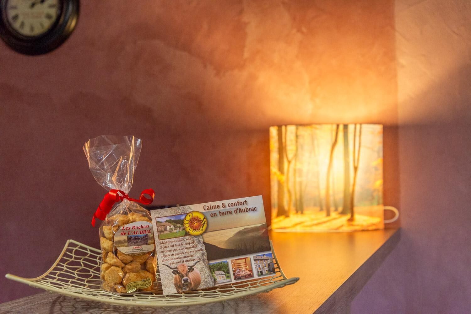 Een dienblad met een verpakte snack, een brochure en een lamp in een warm verlichte kamer.