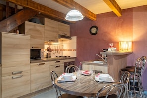 Eine moderne Küche mit Holzschnitzschränken, einem Esstisch mit Stühlen und einer Wanduhr.