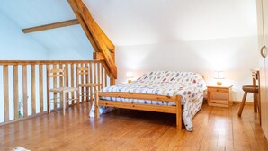 Un dormitorio con una cama de madera, dos mesitas de noche, una silla y una barandilla de madera.