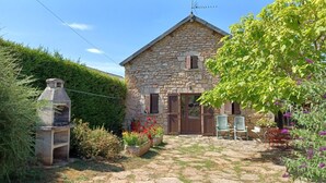 Una casa de piedra con chimenea, una puerta y un porche pequeño con sillas.