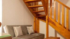 Una escalera de madera con un sofá acolchado y una pequeña mesa de madera en una habitación de paredes lisas.