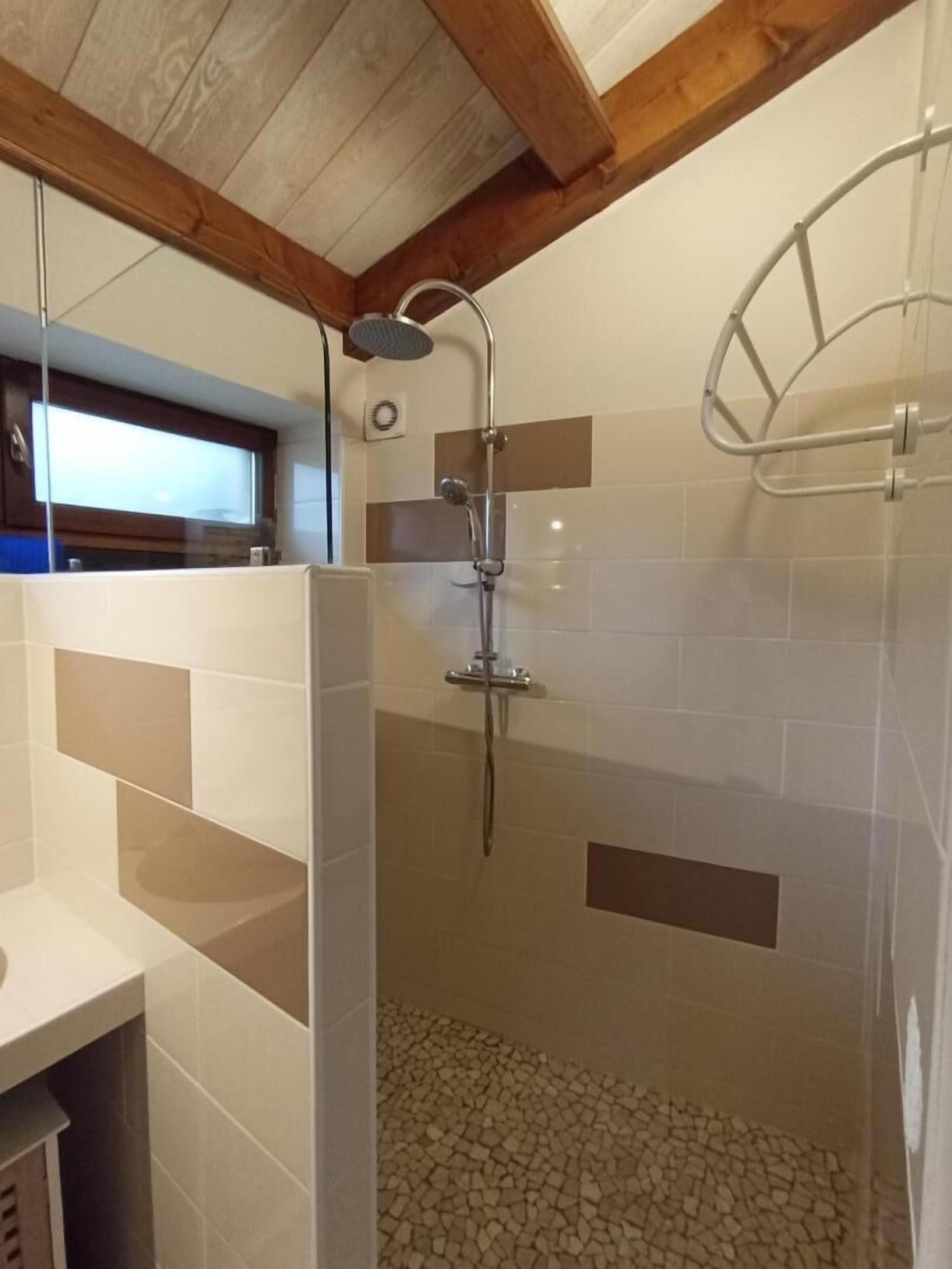Ducha con cabezal de ducha de mano y zona de ducha con cerramiento de vidrio.