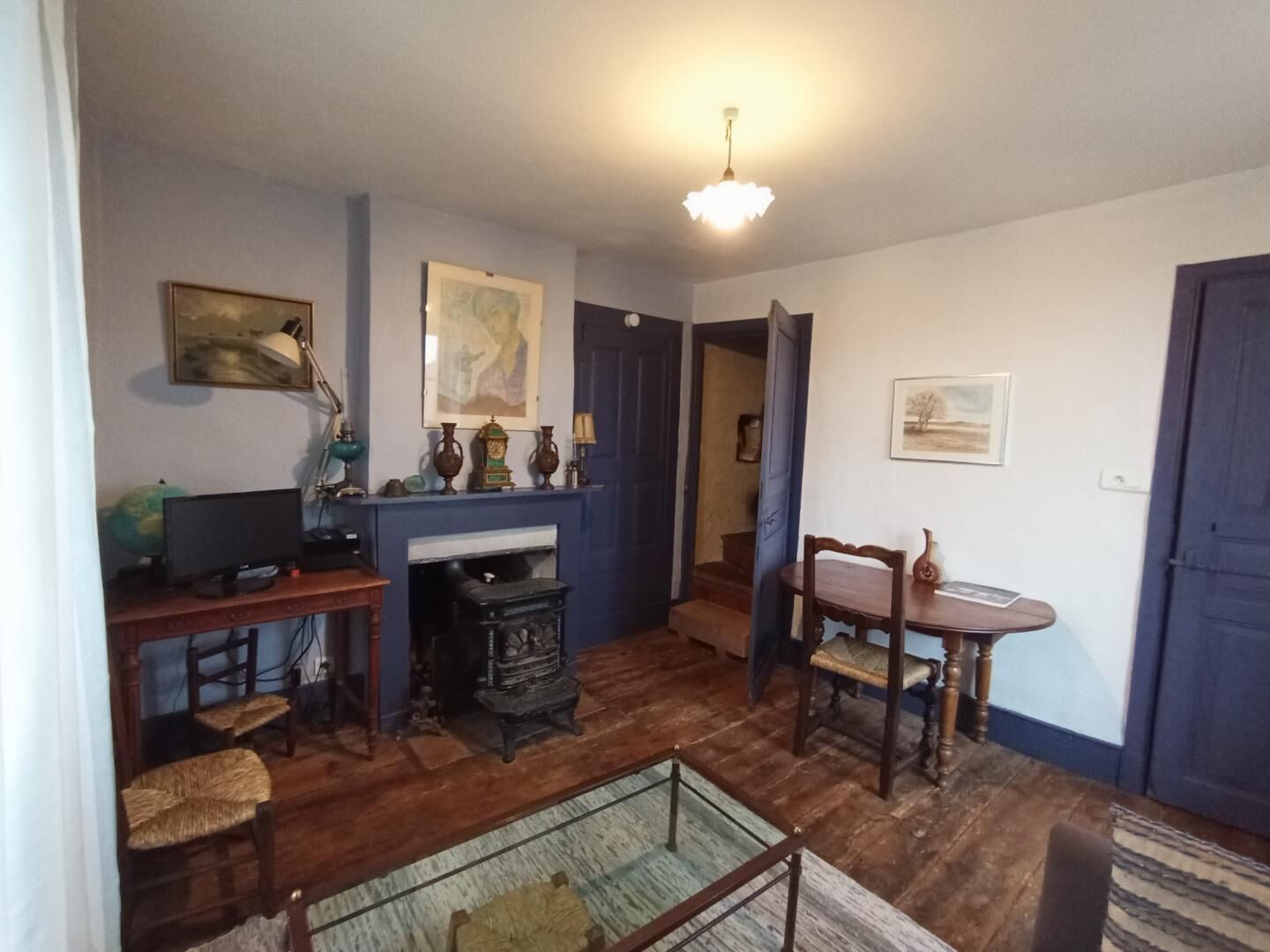 Une pièce avec une cheminée, des meubles en bois, un globe terrestre et un tableau accroché au mur.