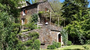 A stone house with a wooden staircase, surrounded by greenery. - Gîtes de France 3 épis 2/3 persons Puychauzier (SAINT-JULIEN-D'ARPAON)