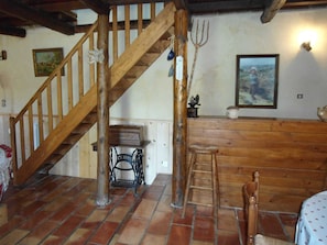 Ein rustikales Interieur mit einer Holztreppe, einer Holztheke, einem Stuhl und einer Leiter.