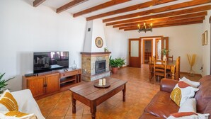 Ein Wohnzimmer mit Fernseher, Holzmöbeln, Kamin und Essbereich.