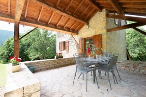 Eine Terrasse im Freien mit Steinboden, Holzboden und einem Tisch mit Stühlen.