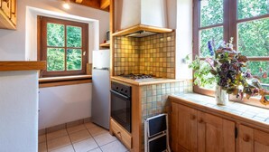 Cocina compacta con estufa, horno y ventana con vistas a árboles.