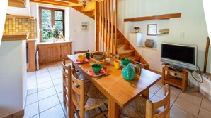 Un comedor con una mesa de madera, sillas, un televisor y una escalera.