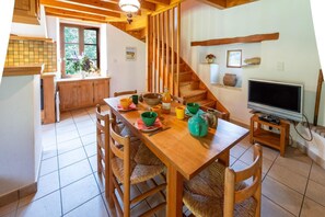 Ein Essbereich mit einem Holztisch, Stühlen, einem Fernseher und einer Treppe.