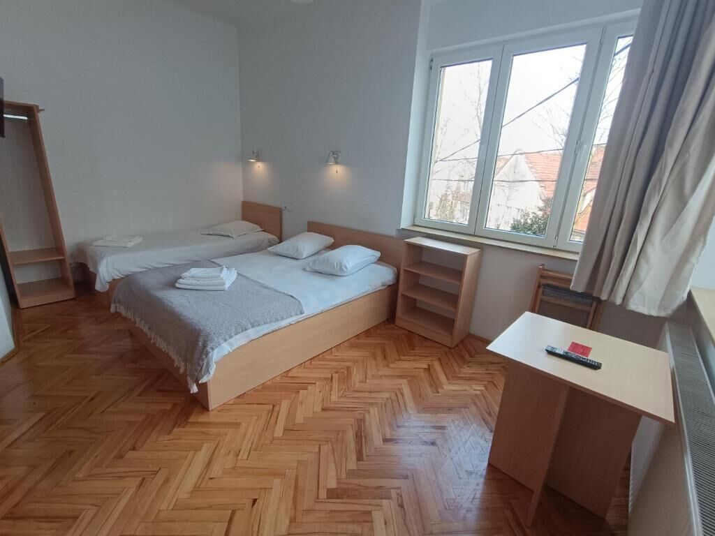 A bedroom with two beds, a desk, and a window.