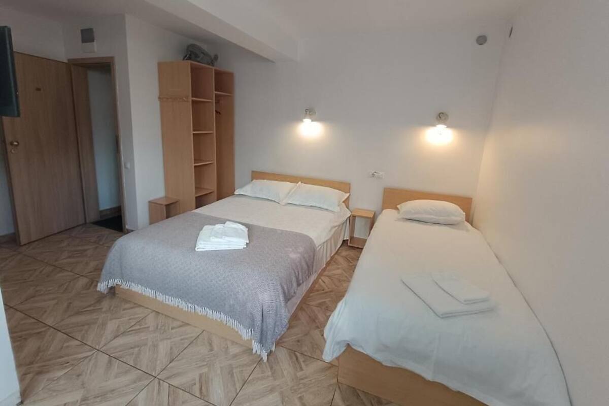 A bedroom with two beds, a wardrobe, and a shelf unit.
