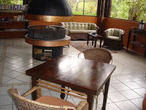 Un ambiente interior acogedor con una mesa redonda, sillas de mimbre, un sofá y una chimenea grande.