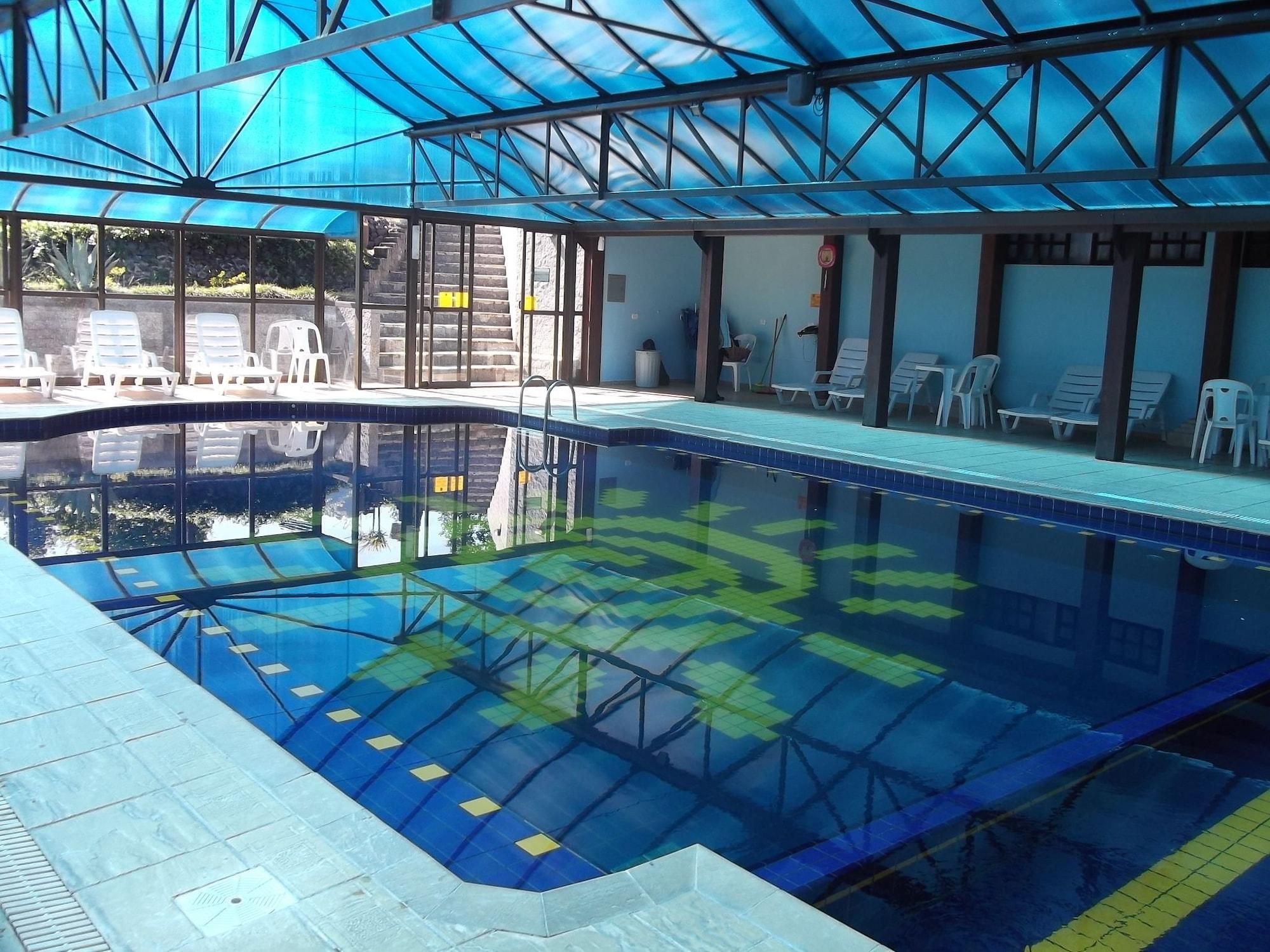An indoor swimming pool with clear water, a tiled deck, and lounge chairs.