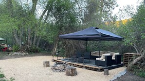 An outdoor seating area with a covered table and chairs, surrounded by trees. - Charming cabin tent campground in peaceful Frenchtown for your getaway (Frenchtown)