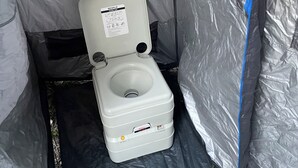 A portable toilet with a seat and lid, labeled 'SEAFLO,' inside a tent-like structure with a blue zipper. - Charming cabin tent campground in peaceful Frenchtown for your getaway (Frenchtown)