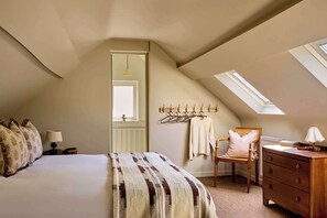 A bedroom with a sloped ceiling, a bed, a dresser, a chair, and a coat rack. - The Little Duke | Cosy Hideaway near Southwold (Halesworth)