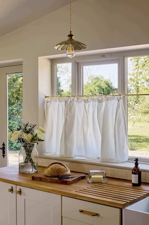 A kitchen with a wooden countertop, a loaf of bread, a bottle of soap, and a vase with flowers. - The Little Duke | Cosy Hideaway near Southwold (Halesworth)