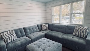 Modulaarinen sohva, jossa on napitettua kangasta, kattotuuletin ja ikkuna, jossa on sälekaihtimet.