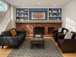 A living room with a fireplace, a sofa, a coffee table, and a bookshelf.