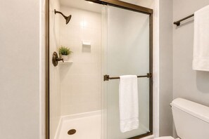 A glass-enclosed shower stall with a towel rack and a small plant on the wall.