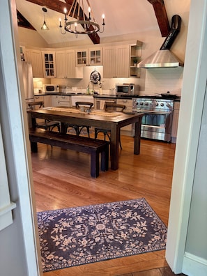 A spacious kitchen with wooden flooring, a central island, and modern appliances.