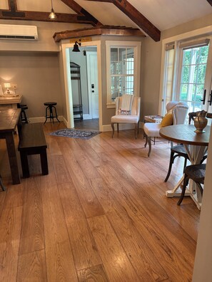 Une pièce dotée d’un plancher en bois, d’une table à manger, de chaises, d’un banc et d’un passage menant à une autre pièce.