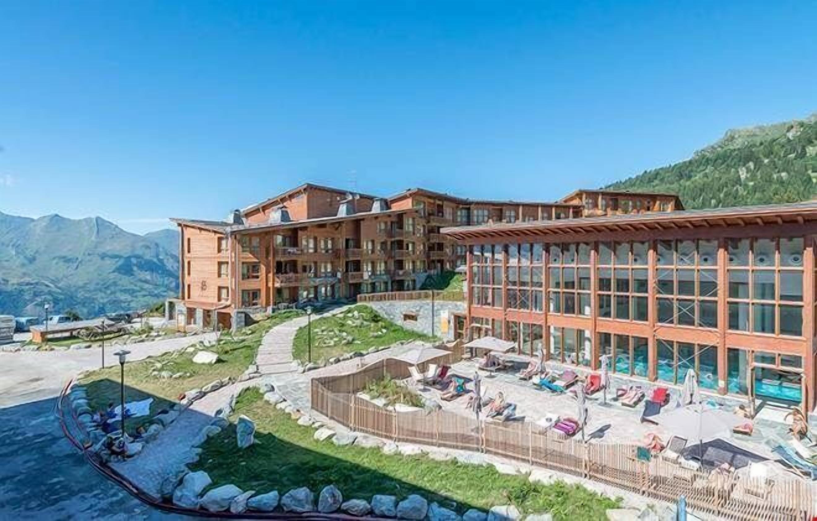 A hotel with multiple floors, outdoor seating areas, and a pool.