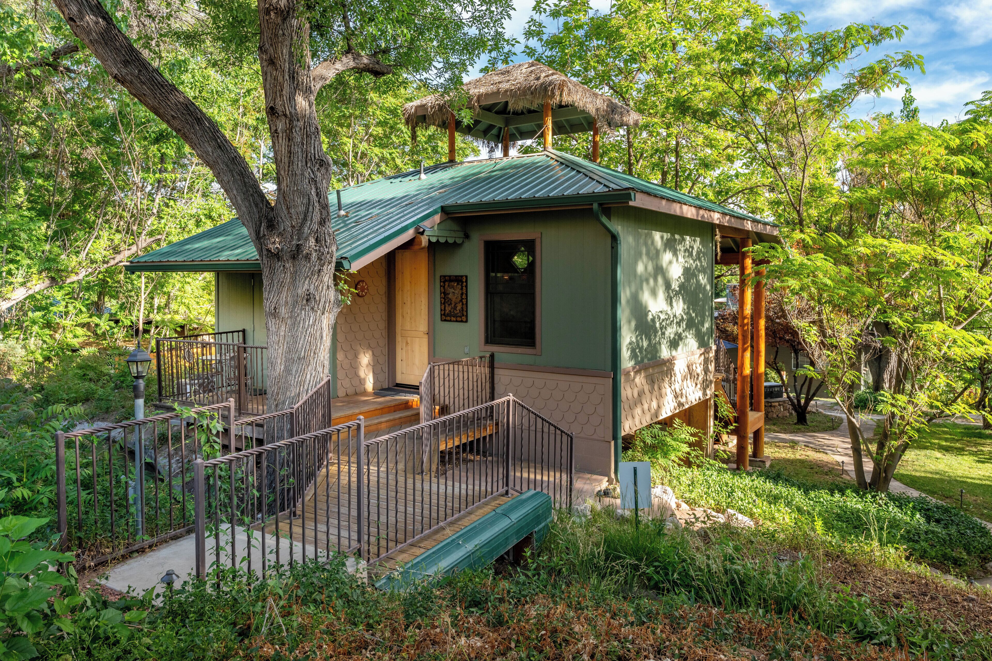 Un petit bâtiment d’un seul étage, doté d’un toit végétalisé, entouré d’une végétation luxuriante et d’arbres.