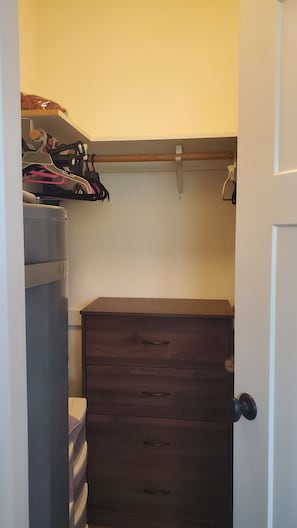 Un armario con un aparador de madera, una estantería con ropa y una puerta.
