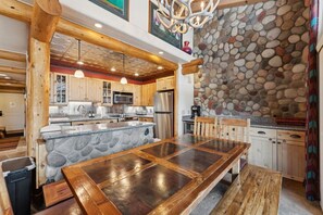 A kitchen with a stone island, wooden cabinets, and a stone wall. - Lionshead Living | Steps from Gondola + Pool (Vail)