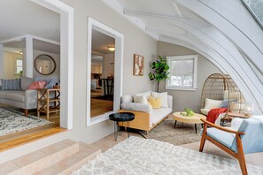 Ein gemütliches Wohnzimmer mit einer Couch, einem Couchtisch und einem Sessel. Eine Treppe führt in einen anderen Raum.