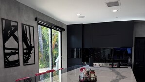 A modern interior with a marble floor, recessed ceiling lights, and a large window with a view of greenery.