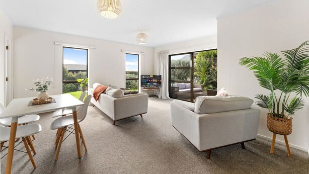 A modern living room with a dining area, large windows, and a view of the outdoors. - Charming single-level home - just moments from the beach,  sun-soaked garden. (Auckland)