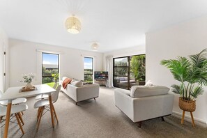 Una sala de estar moderna con comedor, ventanas amplias y vistas al exterior.