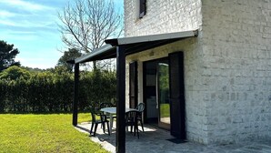 A house with a stone exterior, a covered patio with chairs, and a grassy yard. - Beautiful cottage with garden Resort Adamo& Eva (Numana)