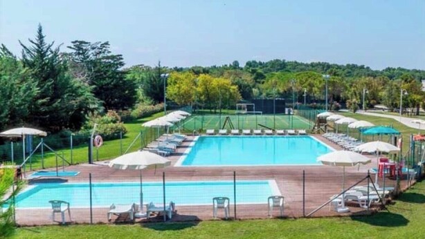A rectangular swimming pool with a surrounding deck, lounge chairs, and umbrellas. - Beautiful cottage with garden Resort Adamo& Eva (Numana)