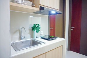 A kitchen with a stainless steel sink, a modern stove hood, and a digital scale on the countertop. - Comfy And Bright 2Br At Pollux Chadstone Apartment (Cikarang)