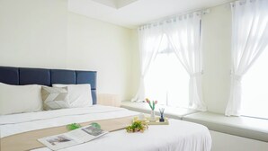 Een hotelkamer met een bed, een vensterbank en een nachtkastje met een tijdschrift, bloemen en een dienblad.