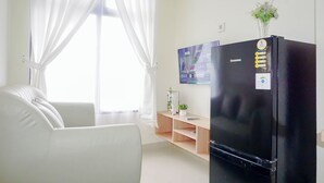Een moderne woonkamer met een zwarte koelkast, een witte bank en een houten plank met een potplant.