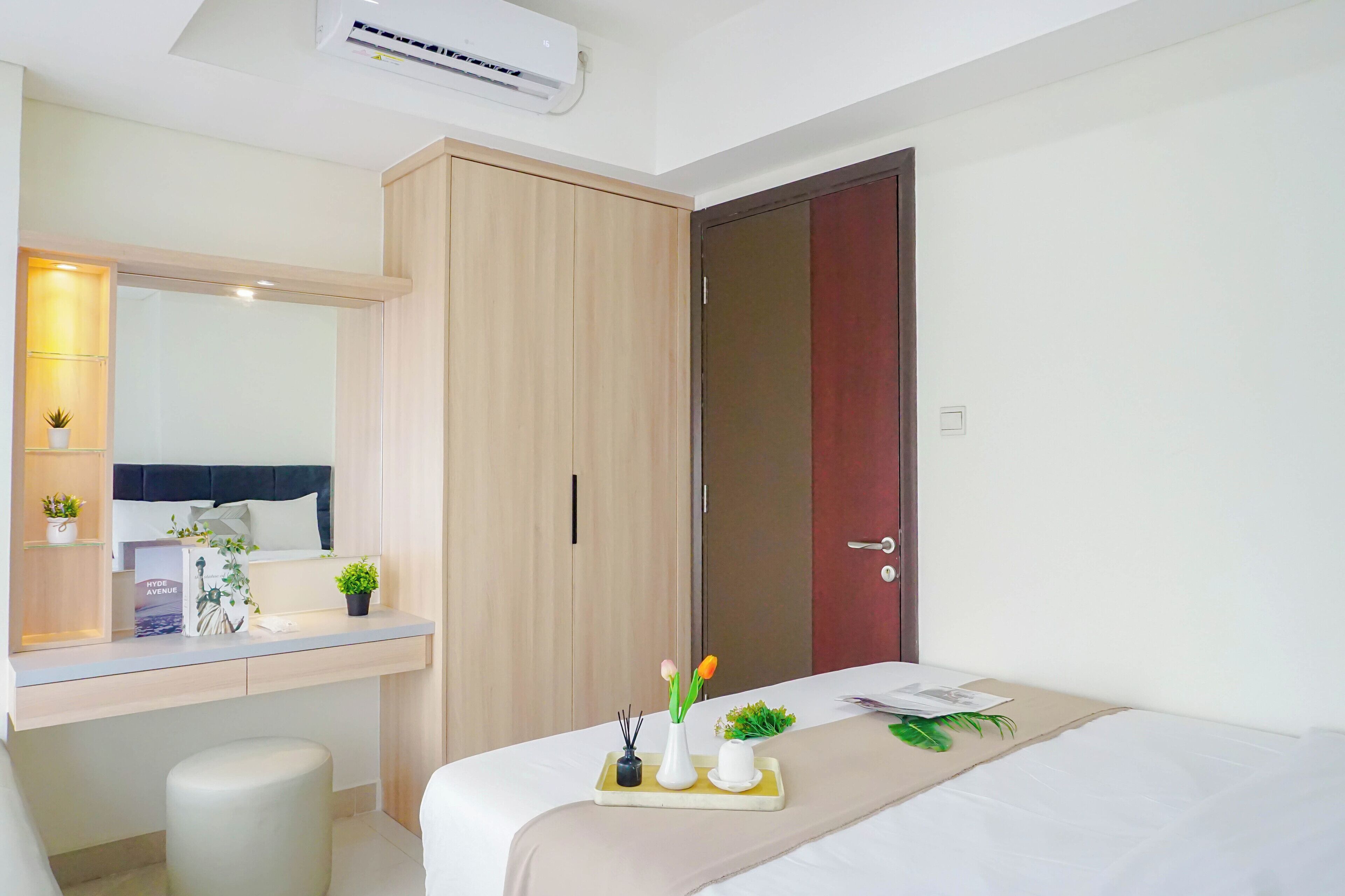 A modern hotel room with a bed, bedside table, and a wardrobe.