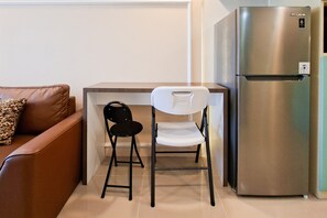 Eine Küchenzeile mit einem Edelstahlkühlschrank, einem braunen Ledersofa und einem weißen Stuhl.