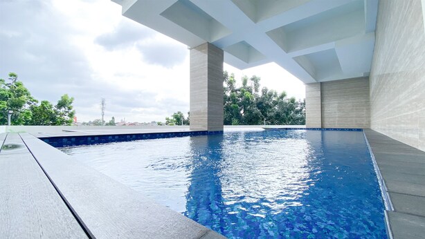 Ein Schwimmbecken mit moderner Architektur, umgeben von einer angelegten Grünfläche mit Bäumen.