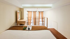 Ein Hotelzimmer mit Bett, Schreibtisch, Spiegel und einem Fenster mit Vorhängen.