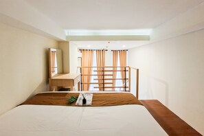 Ein Hotelzimmer mit Bett, Schreibtisch, Spiegel und einem Fenster mit Vorhängen.