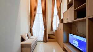 Ein modernes Wohnzimmer mit Sofa, Fernseher, Holzregalen und Vorhängen.